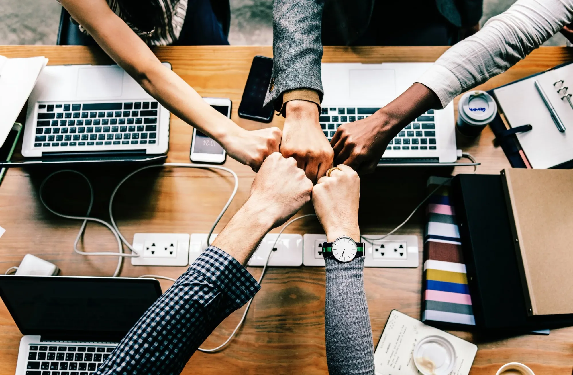 Educators joining hands together over a meeting table